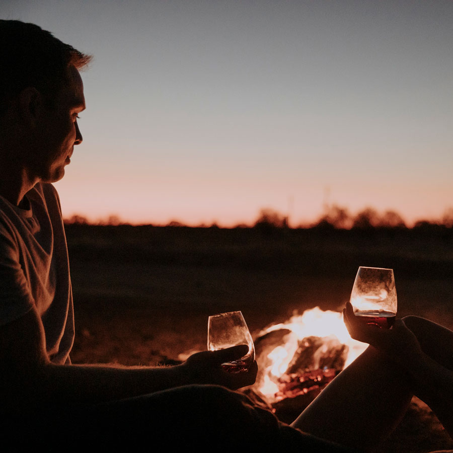 couple-with-firepit-romance-package_900x900 Couple sitting by fire pit with glass of wine