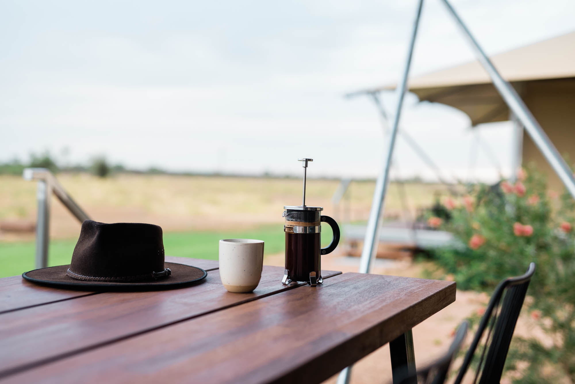 Coffee and Akubra hat on the verandah of a glamping tent.