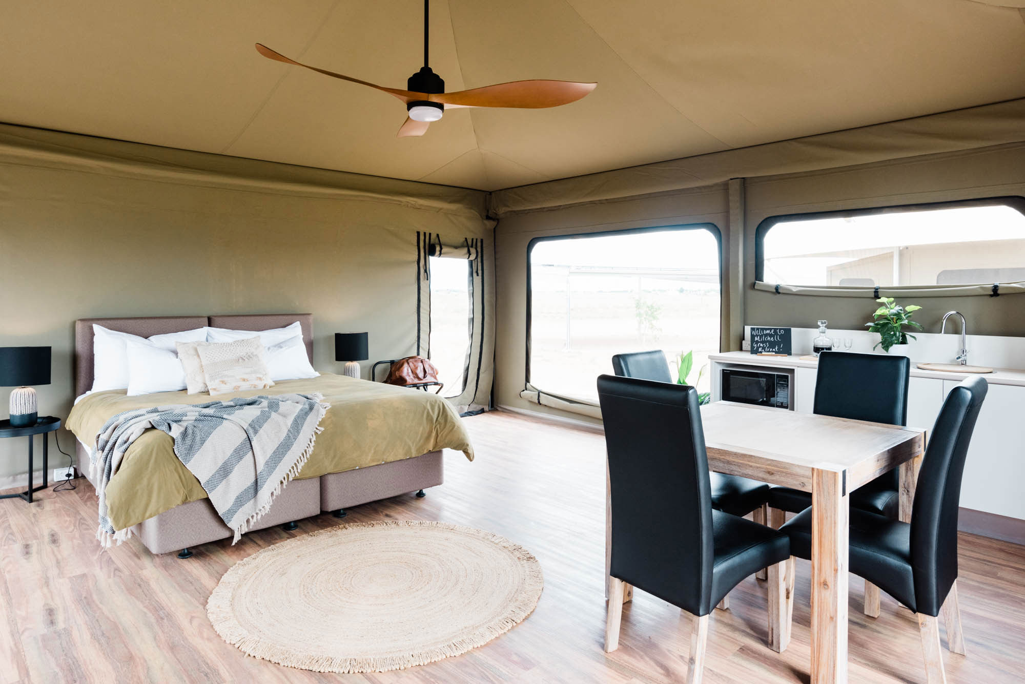 Inside the spacious Mulga Tent which includes a double bed, table and chairs, kitchenette and kids swags in the corner.