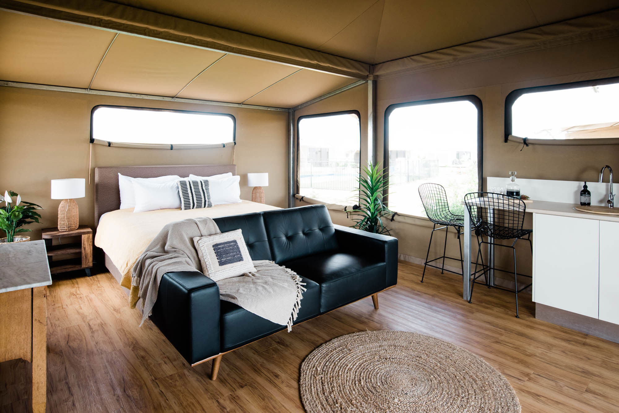 Luxury bedding and couch area inside glamping tent.